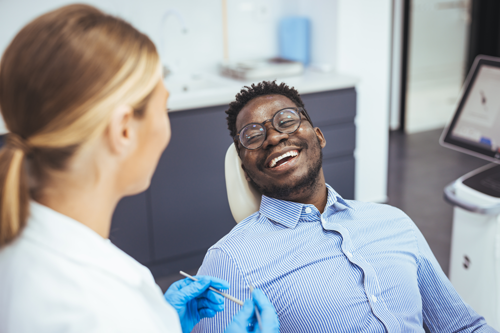 Smiling patient consulting with dentist in modern clinic