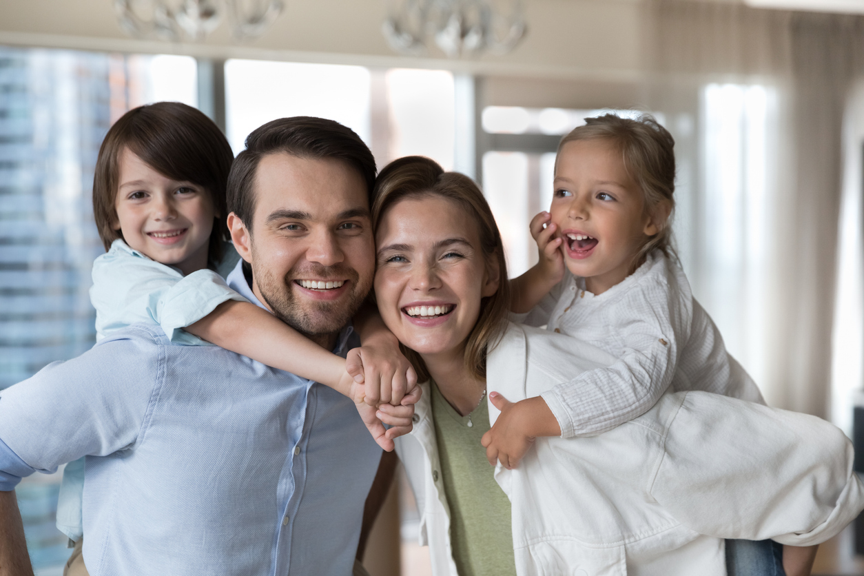 Happy family with kids piggybacking – Trillium Dental smiles